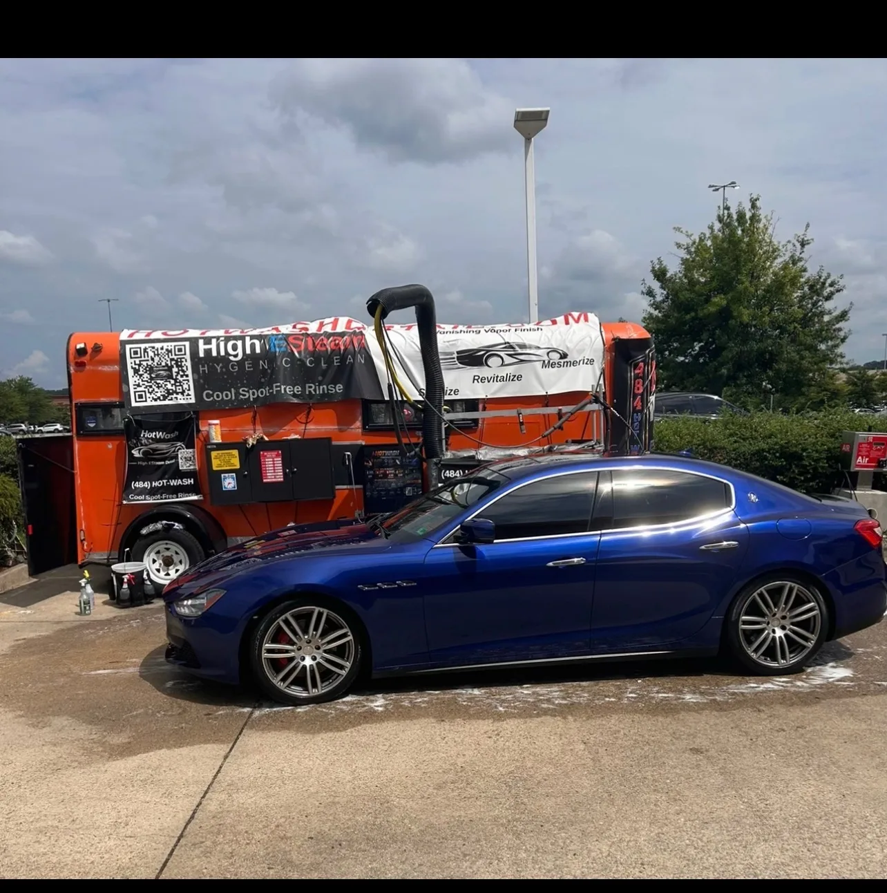 Blue car beside the HotWash mobile detailing trailer